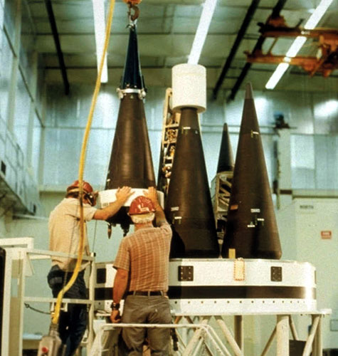 U.S. technicians secure reentry vehicles housing warheads to a MIRV bus